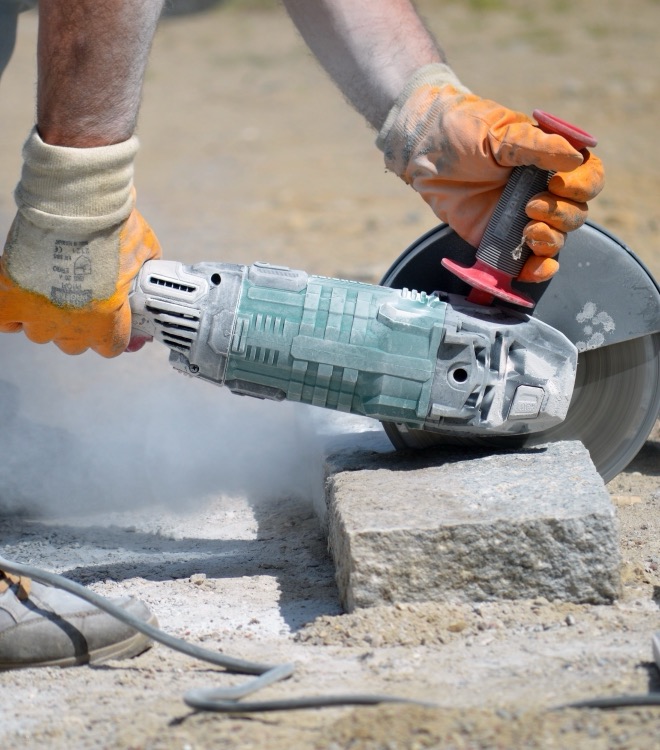 Artisan découpant une pierre de granit à la disqueuse sur un chantier